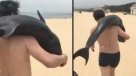 Captan a turista llevando sobre sus hombros a un delfín para \
